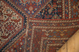 Vintage Qashqai rug corner showing madder red and blue geometric panels with woven foundation.