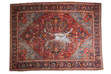 Antique Heriz carpet: ruby red field, sapphire blue medallion, geometric pattern, central patina. 9'6
