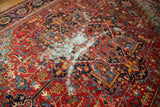 Isolated distress with exposed foundation on geometric antique Heriz rug.