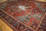 Antique Heriz carpet's gem-tone geometric patterns with clear isolated wear and exposed foundation.