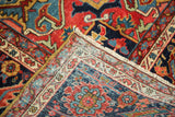 Folded corner of the hand-knotted Heriz rug, with ruby red, navy, and pale blue geometric patterns.