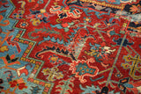 Heriz carpet's vivid ruby red and pale sapphire blue patterns, showing central foundation distress.