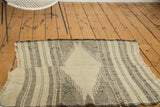 Geometric ivory and charcoal striated stripes on vintage Kurdish rug detail, with tattered end.