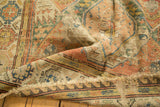 Detail of Antique Soumac carpet's hand-knotted geometric lattice, rich colors, and frayed end.