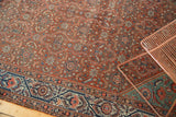 Corner of vintage Malayer carpet with intricate indigo border and floral red field.