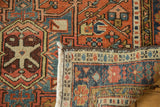 Hand-knotted vintage Karaja rug, folded corner revealing pile, fringe, and a geometric red and blue border.