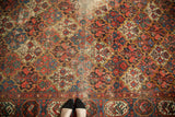 Traditional Persian Baktiari carpet's intricate floral panel field in madder red, blue, and beige, showing wear.