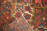 Hand-knotted Baktiari rug with intricate floral pile, exposed foundation, and areas of wear.