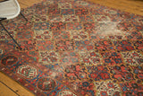 Baktiari carpet field: madder red, sky blue scalloped panels, germinating trees, pile wear.