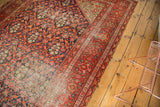 Section of antique Malayer runner, revealing low pile, intricate floral field, and geometric red border.