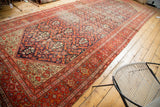 Antique Persian Malayer rug corner, intricate red borders frame a navy blue floral design.