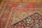 Antique hand-knotted Persian Malayer rug corner, showing geometric terracotta and navy patterns.
