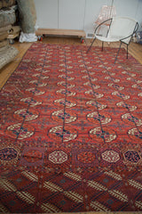 Traditional antique Tekke carpet with distressed red guls and a geometric navy border.