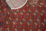 Distressed texture of an antique Tekke carpet with geometric gul pattern in brick red, navy, and aubergine.