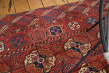Distressed surface of antique Tekke carpet showing repeating geometric gul motifs in brick red and navy.