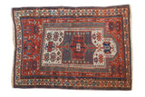 Antique Caucasian rug featuring a geometric prayer mehrab in brick red, ivory, and blues.