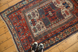 Antique Caucasian rug section with geometric prayer mehrab design in brick red, blue, ivory, and teal.