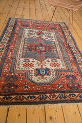 Hand-knotted fringe and geometric blue, brick red, ivory border patterns of the antique Caucasian rug.