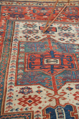 Antique Caucasian rug: geometric prayer mihrab in brick red, sky blue, teal, and ivory.