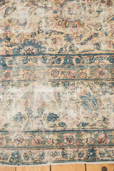 Textured field of a vintage Lavar Kerman rug, featuring blush, ivory, and sky blue floral motifs.