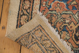 Folded Vintage Mahal carpet, showing fringe, worn pile, and intricate hand knotted foundation.
