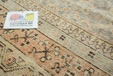 Distressed antique Khotan rug pile with faded apricot, ivory, and teal floral lattice.