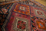 Intricate tribal geometric motifs in tangerine, aubergine, and navy on a vintage Persian carpet.