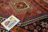 Detailed geometric tribal pattern on vintage Persian rug, featuring tangerine, aubergine, and navy shades.