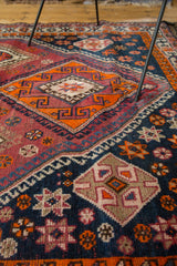 Textured hand-knotted geometric tribal pattern in tangerine, aubergine, and navy.