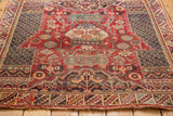 Vintage Sirjan rug detail showing charcoal lattice border, cherry red field, and fringe.