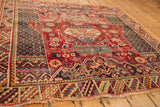 Detail of the vintage Sirjan rug's vibrant geometric borders, lattice fills, and colorful fringe.