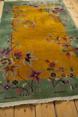 Art Deco rug's pistachio border, gold field, delicate pink blossoms and vinery with fringe.
