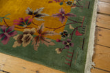 Vintage Art Deco rug corner showcasing pistachio border, gold field, floral vinery, and fringe.