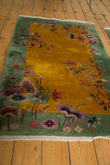Art Deco rug's pistachio border, delicate mauve, pink flowers, and worn white fringe.