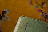 Corner detail of Art Deco rug: gold floral pile, speckled texture, pistachio woven backing.