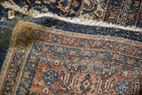 Distressed Bibikabad rug pile revealing intricate terra cotta, blue pattern, exposed foundation.