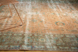 Faded ornate border with time-softened blush and blue floral vinery on distressed Sarouk rug.