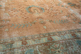 Distressed Sarouk design carpet, with faded blush field, blue vinery, and ornate border.