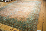 Vintage distressed Sarouk rug corner, time-softened blush field, intricate powder blue florals, ornate green border.