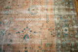 Distressed blush field with blue floral vinery and ornate European-style border.