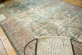Distressed Persian Mahal rug's faded dusty teal, blush floral motifs, and mostly even wear.