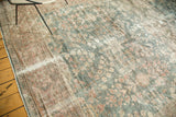Distressed Mahal carpet texture with faded dusty teal floral motifs and exposed foundation.