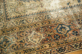 Mahal carpet's distressed border, antique ivory field, dark rust, and forest green vinery.