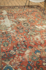 Decorative distressed texture on vintage Mahal carpet in brick red and blue florals.