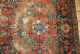 Distressed Persian Mahal carpet with brick red floral field, visible worn texture, and navy border.