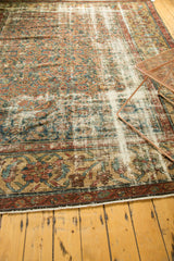 Distressed Mahal carpet corner, highlighting teal, red, gold geometric border and visible foundation.