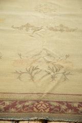 Distressed Indo Chinese rug detail, with faded ivory cloud band bats and worn pale wine red border.