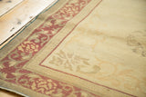 Distressed Indo Chinese carpet corner: pale wine red floral border, geometric trim, worn ivory field.