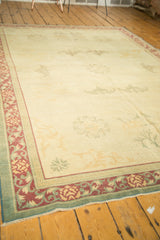 Distressed Indo Chinese carpet corner, pale wine red, sage green floral borders, geometric inner, and worn pile.
