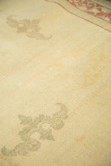 Antique ivory field of the distressed Indo Chinese rug, showing worn sage green cloud band motif.